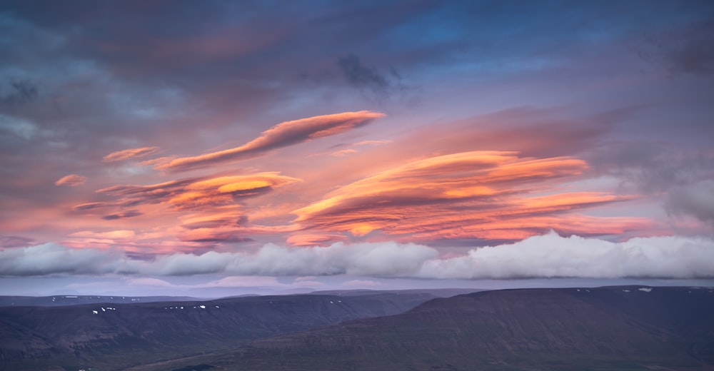 a colorful sunset over a mountain range with clouds in the sky