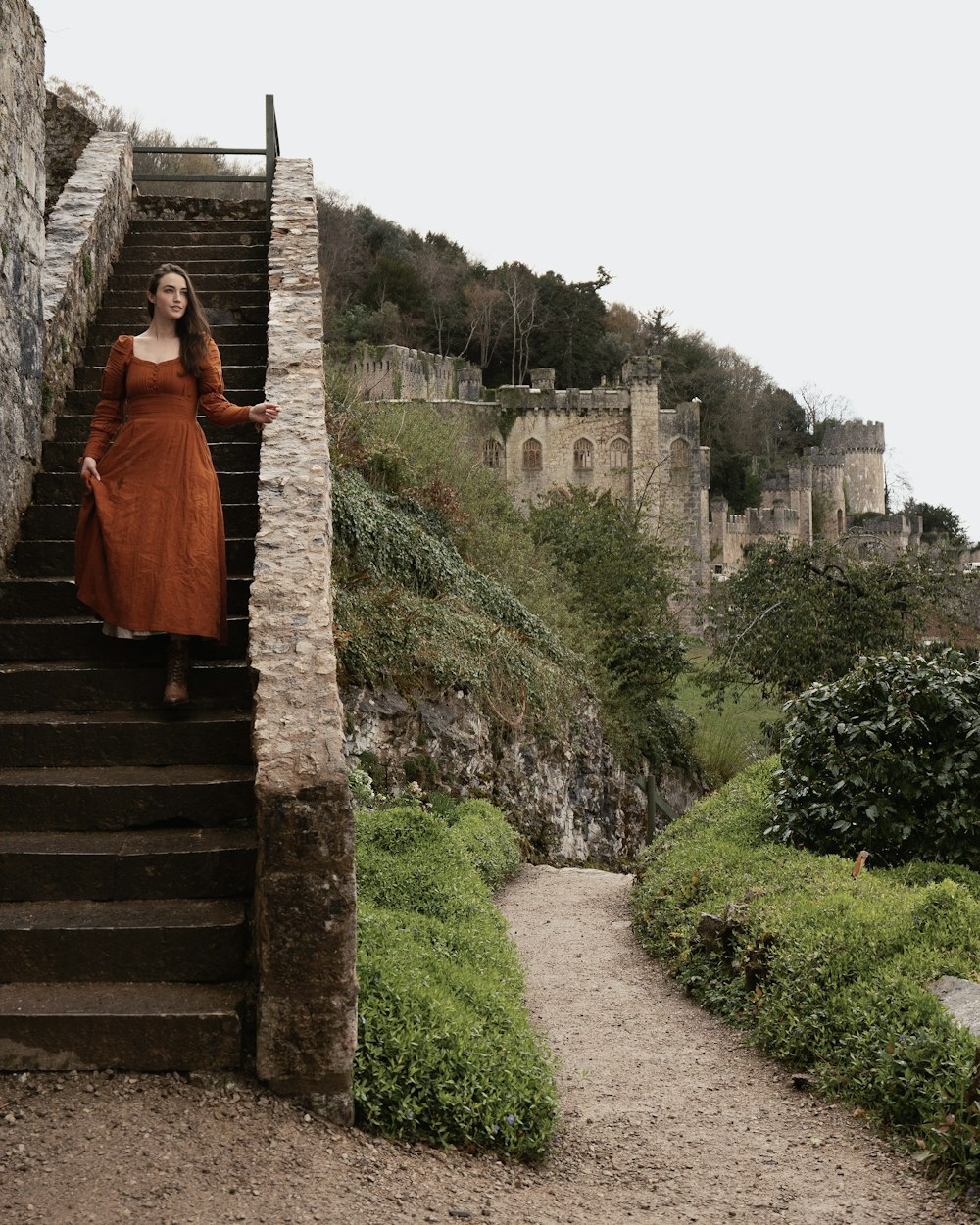 a woman in an orange dress standing on a set of stairs