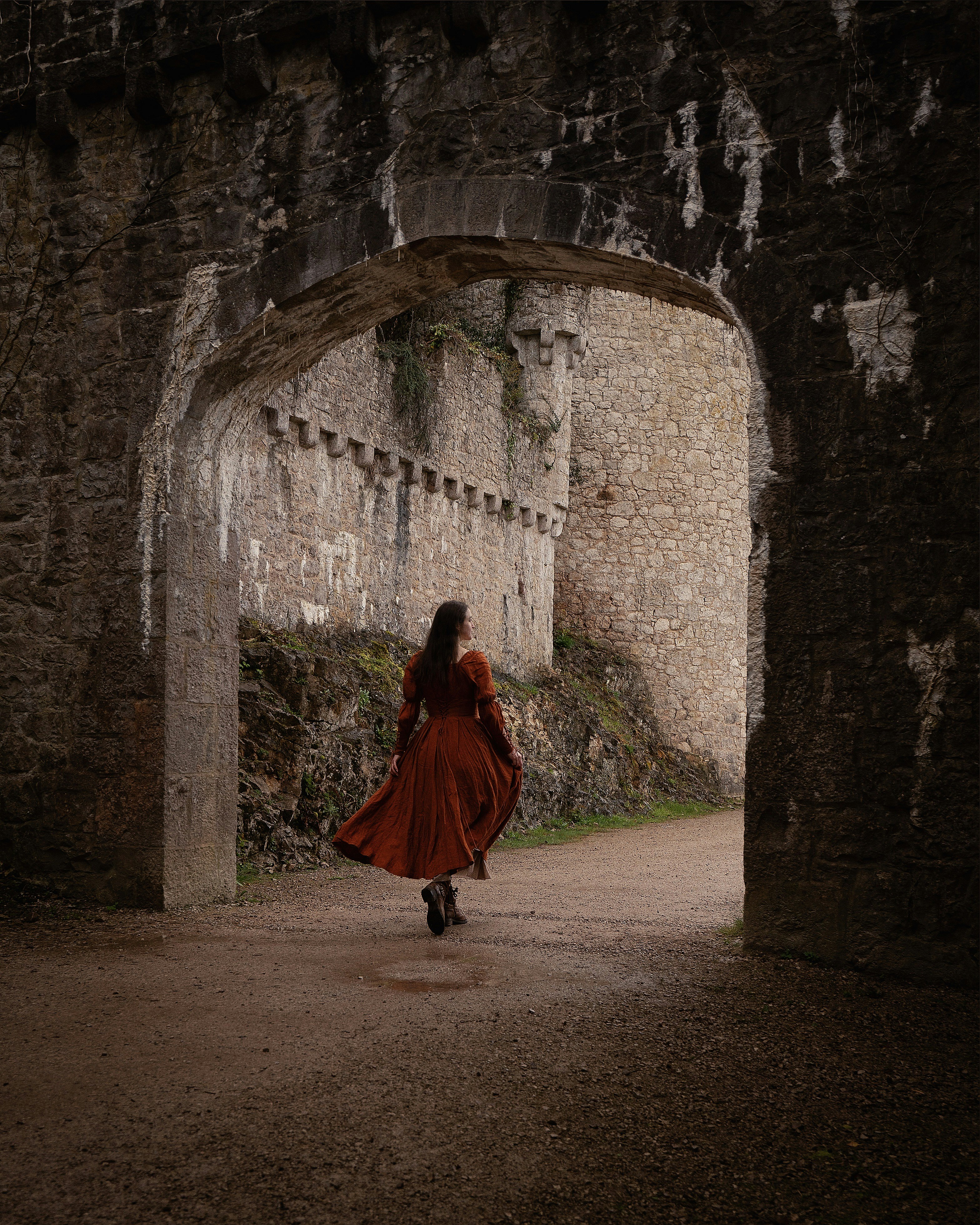 a woman in a red dress is walking through a tunnel