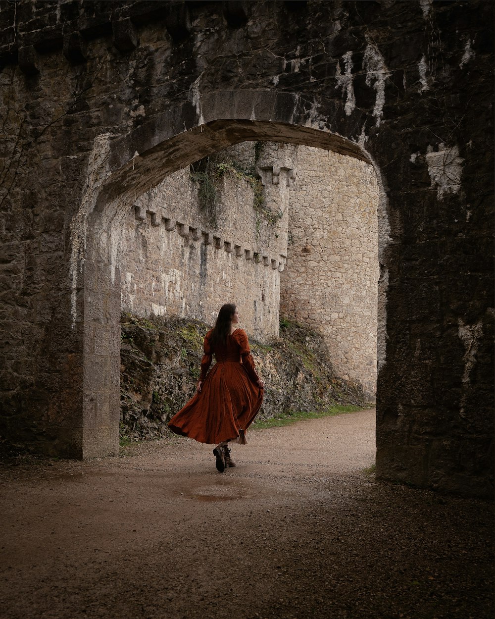 a woman in a red dress is walking through a tunnel