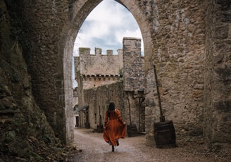 a woman in a red dress is walking through an archway