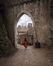 a woman in a red dress is walking through an archway
