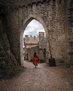 a woman in a red dress is walking through an archway