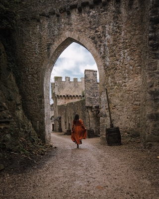 a woman in a red dress is walking through an archway