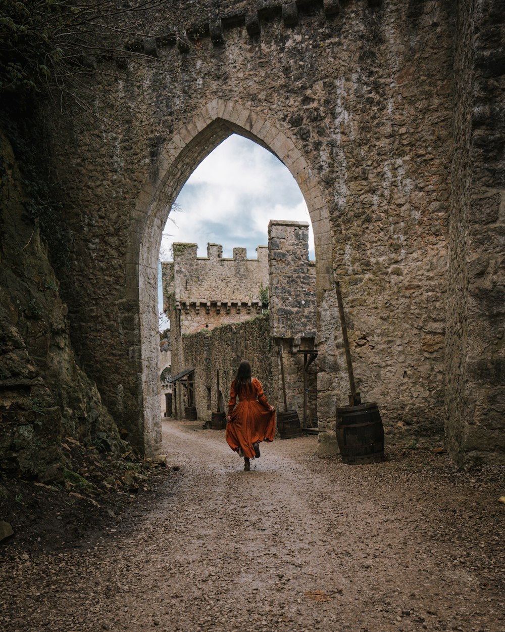 a woman in a red dress is walking through an archway