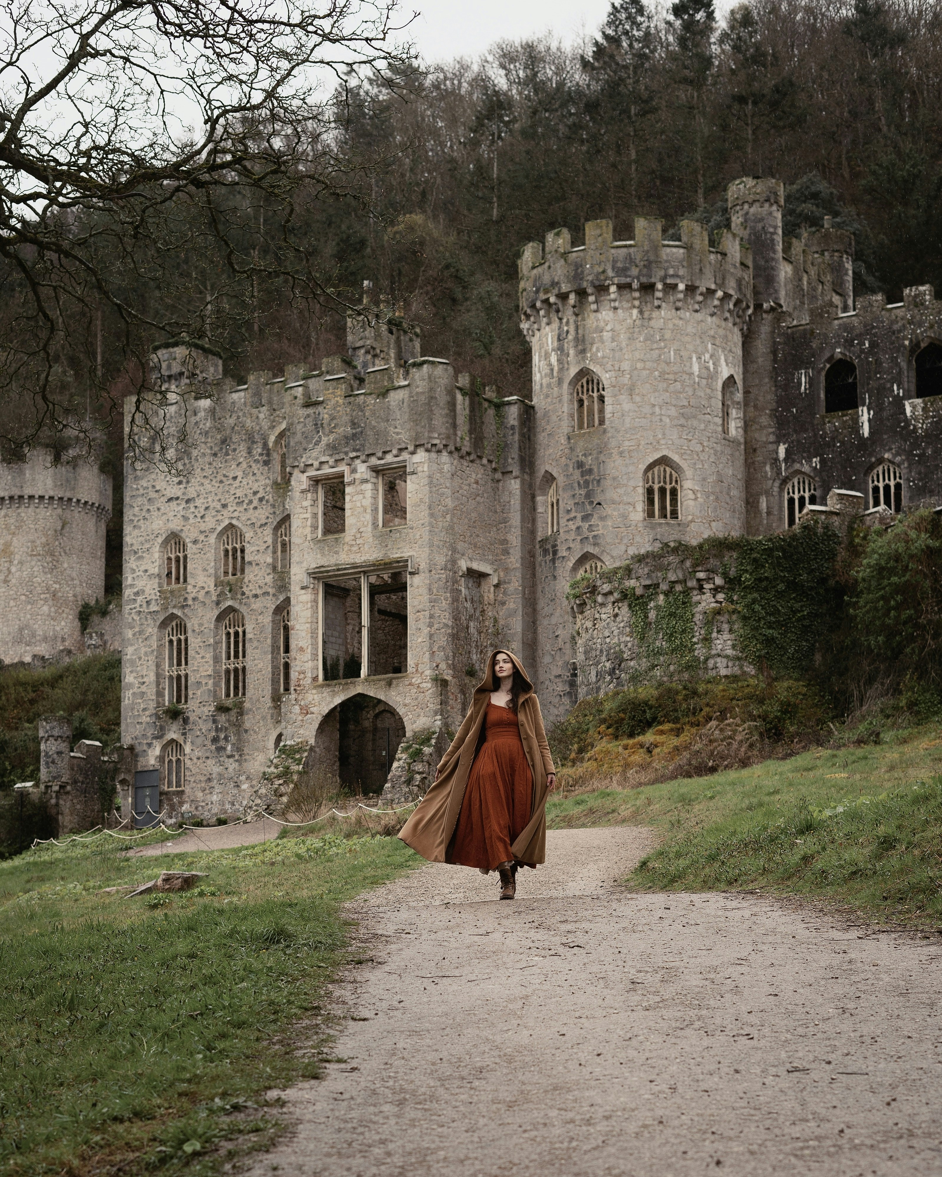 a woman in a long dress walking towards a castle
