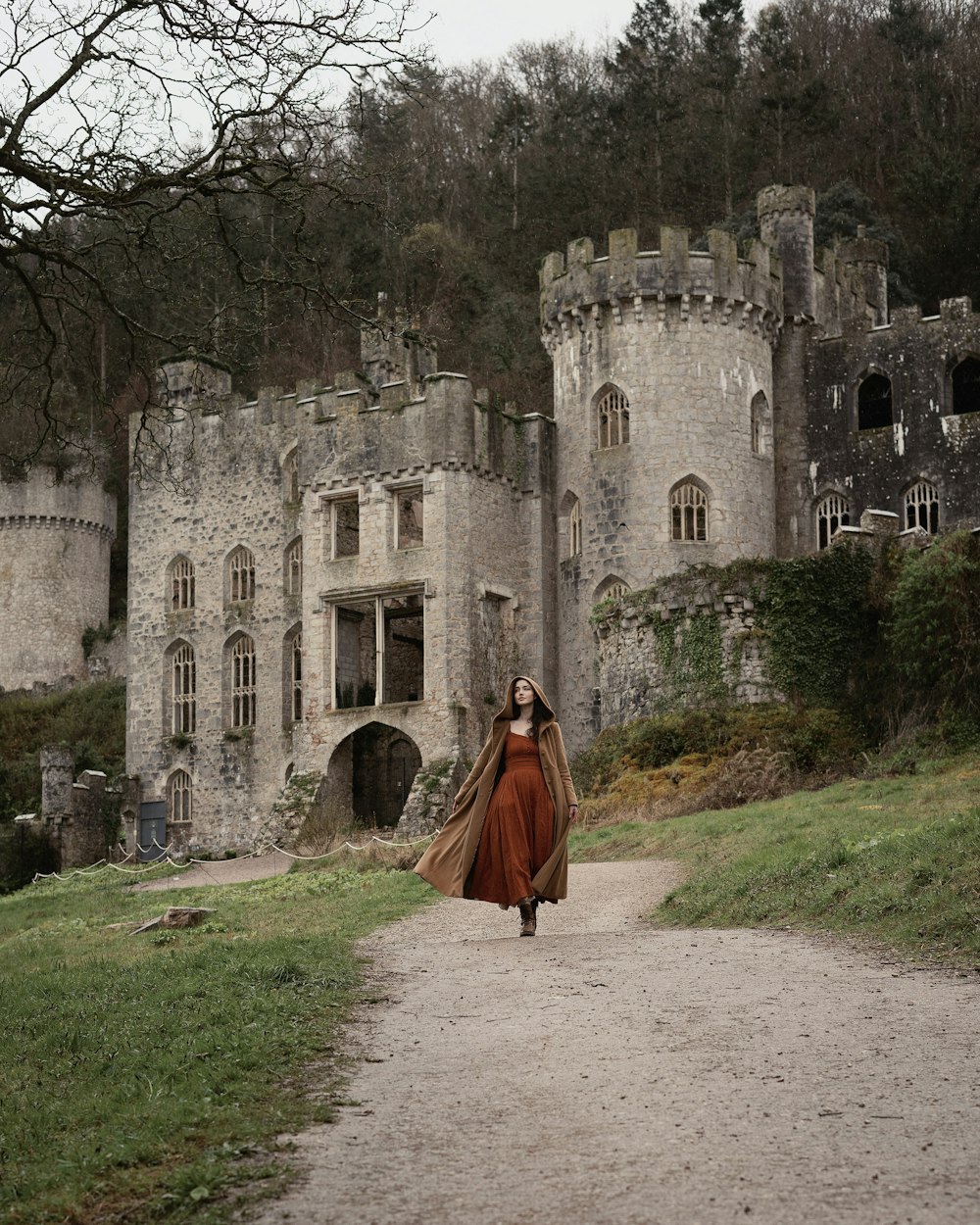 a woman in a long dress walking towards a castle
