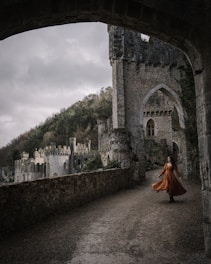 a woman in an orange dress is walking through an archway