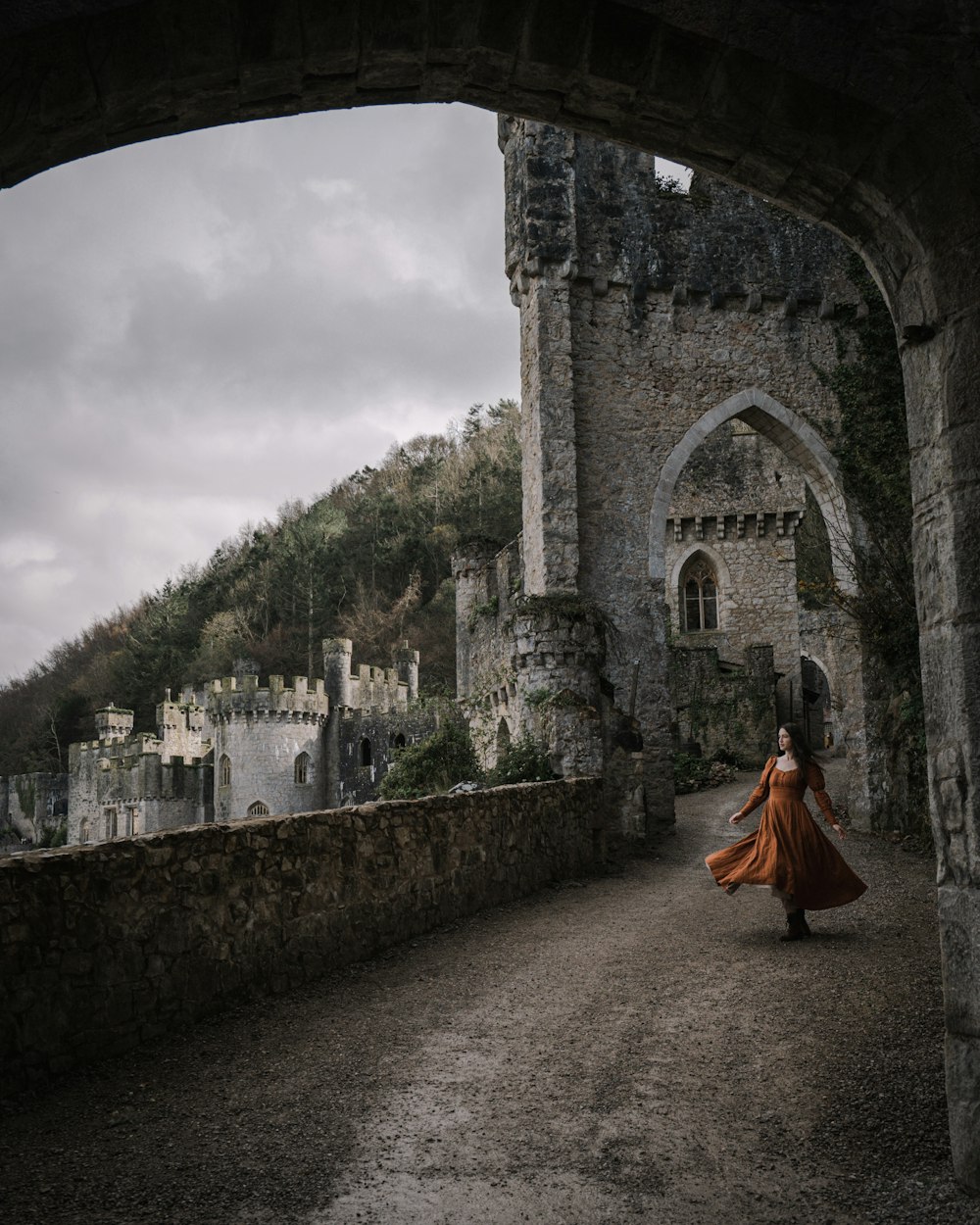 a woman in an orange dress is walking through an archway