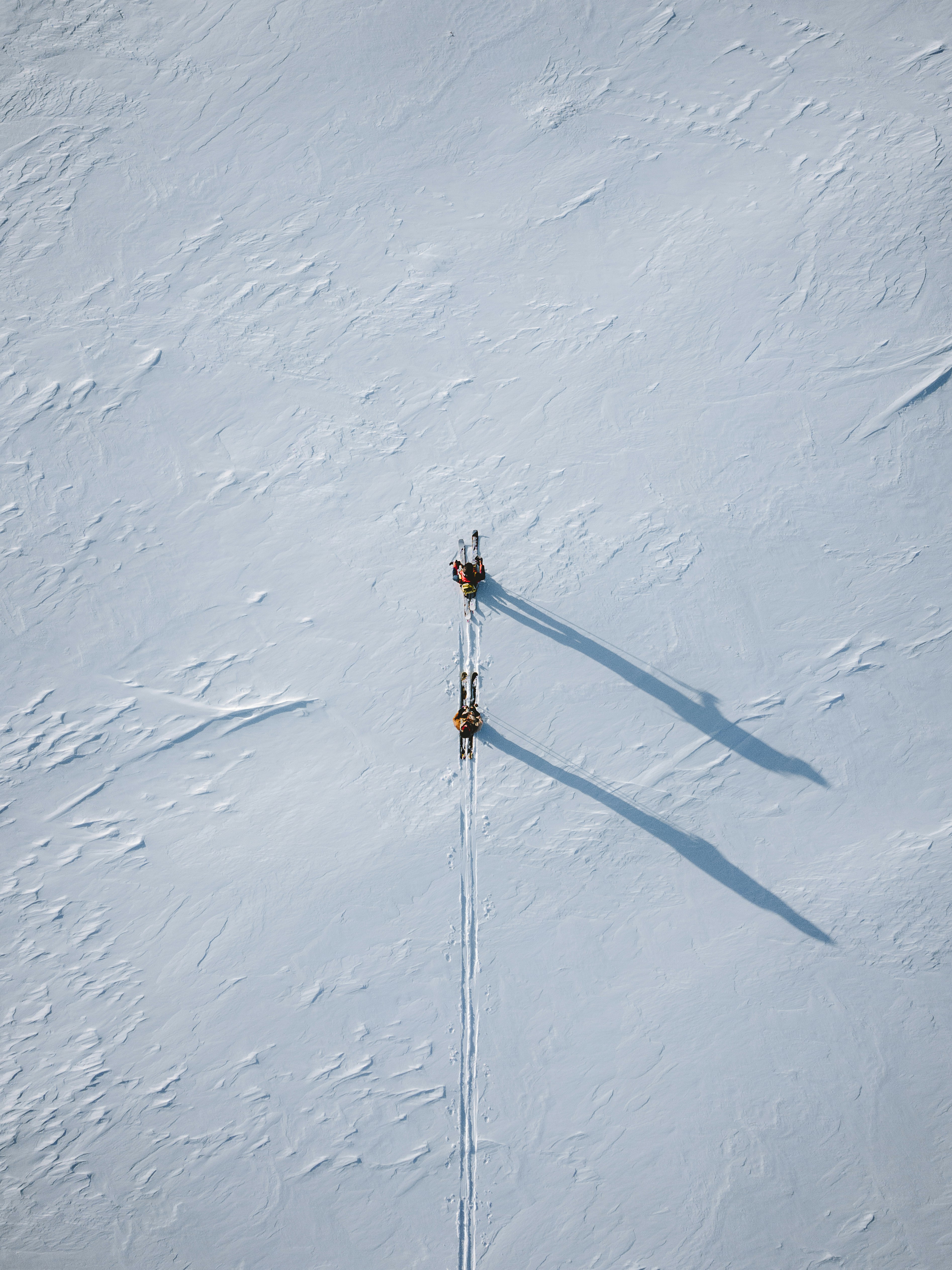 two people are skiing down a snowy hill