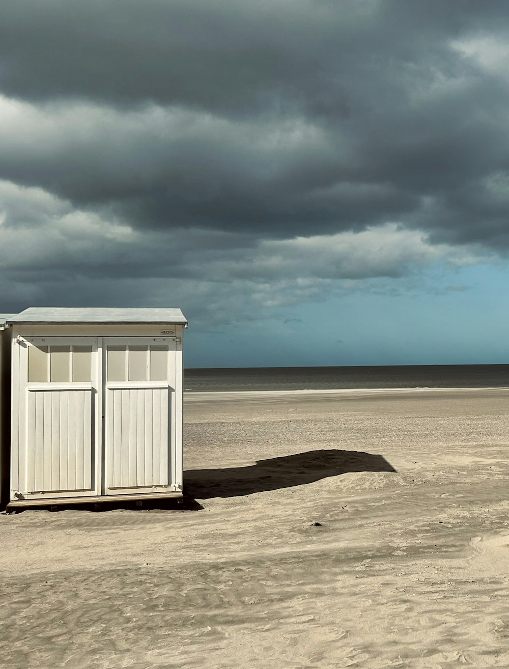 a white outhouse sitting on top of a sandy beach