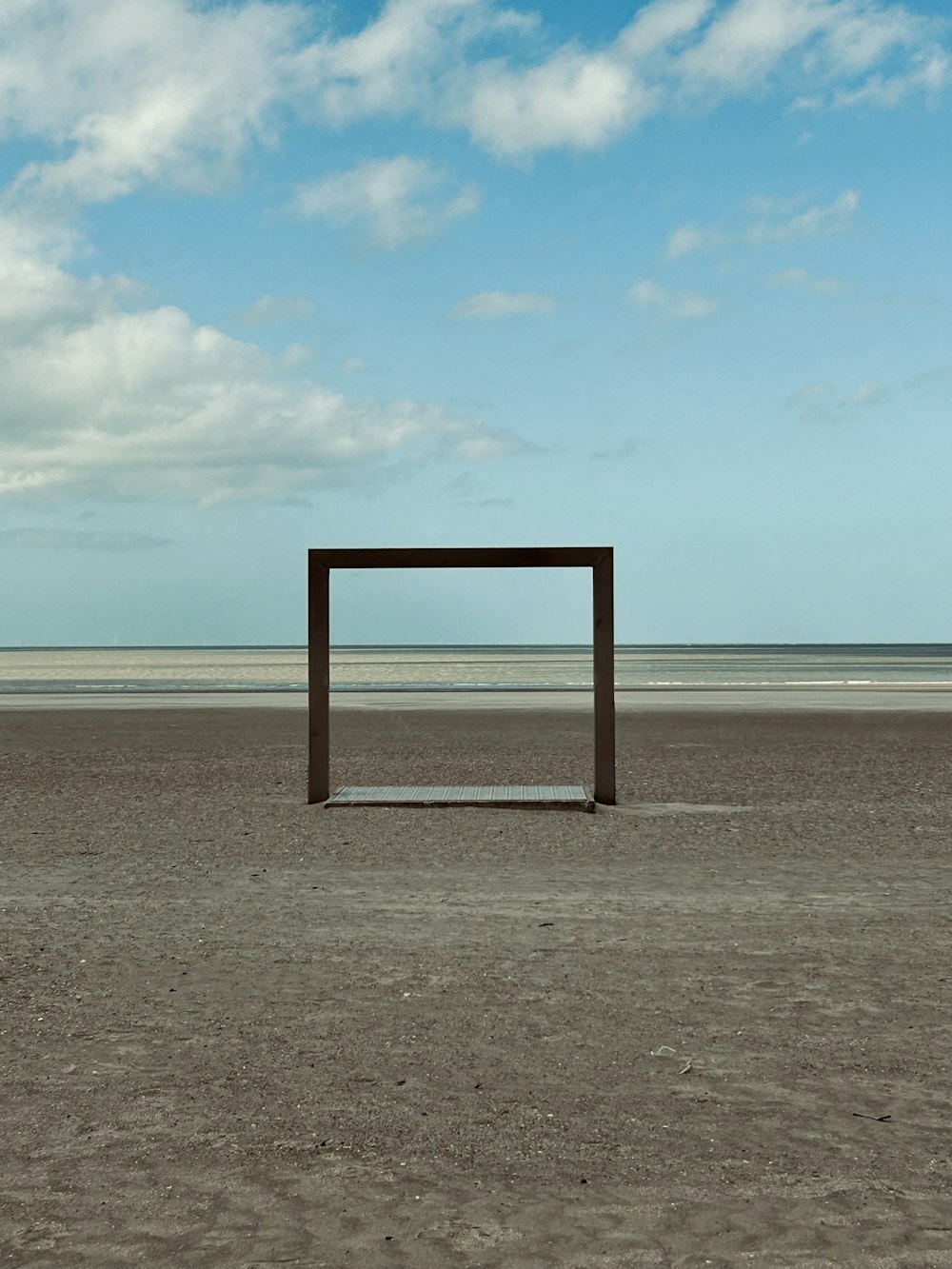 un marco de madera sentado en la parte superior de una playa de arena