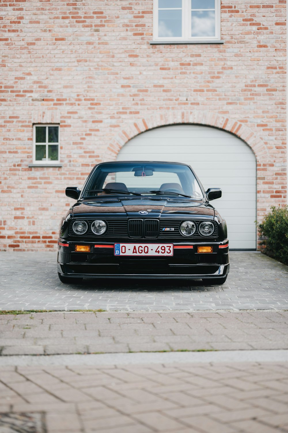 a black car parked in front of a brick building