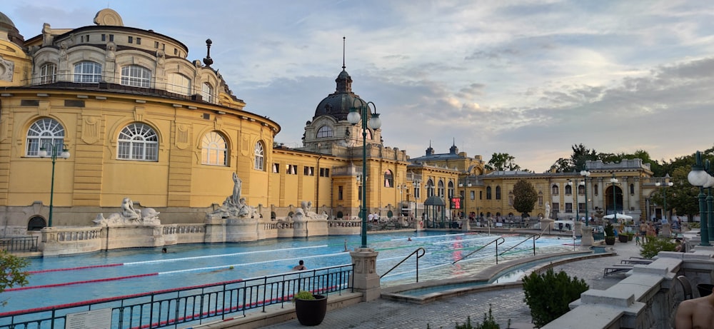 a large yellow building with a pool in front of it