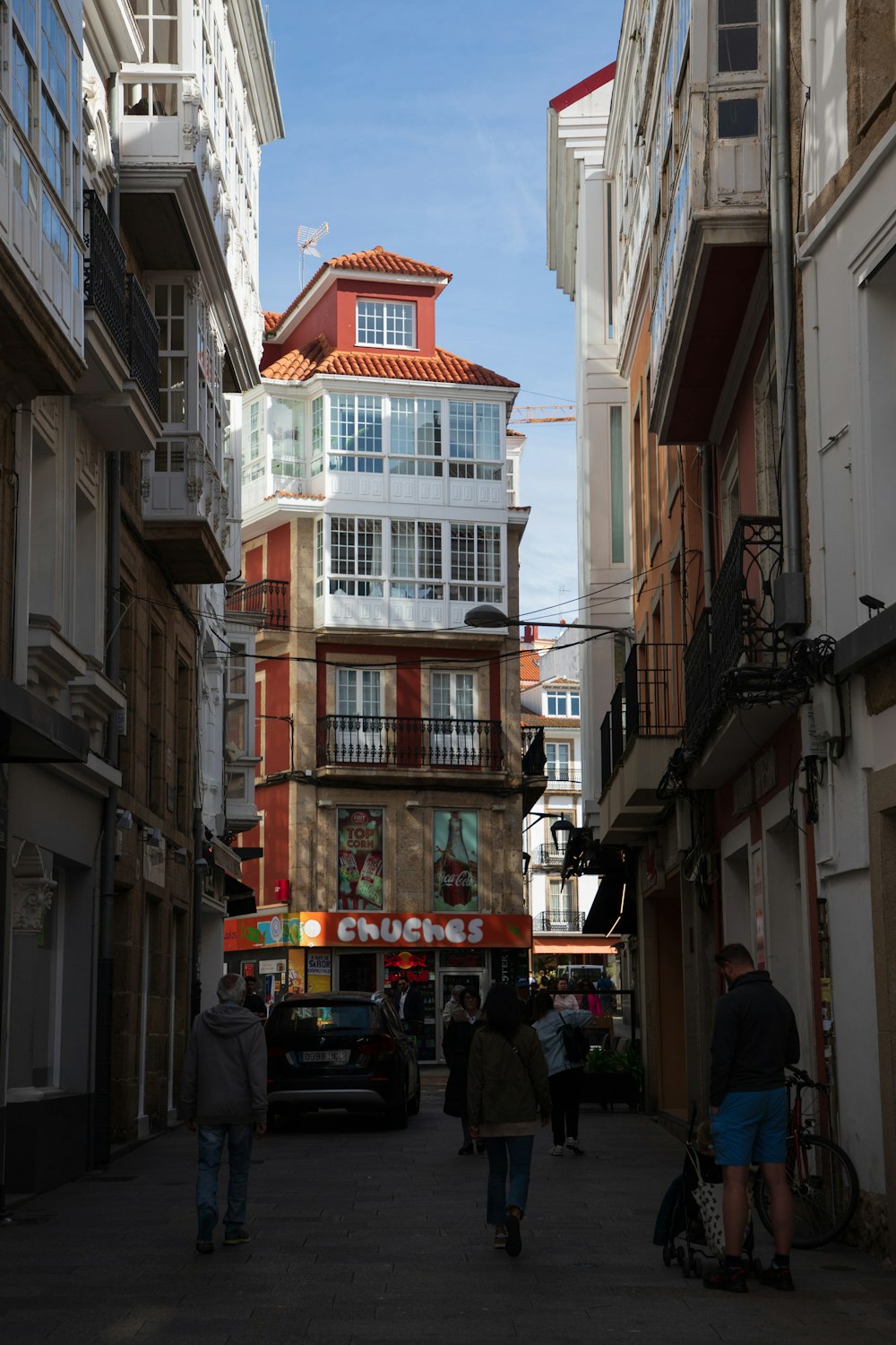 a group of people walking down a street next to tall buildings