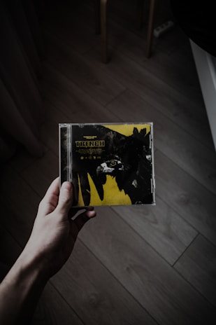 A close-up of hands holding a CD case featuring artwork from a local Ohio band, ready for trade.