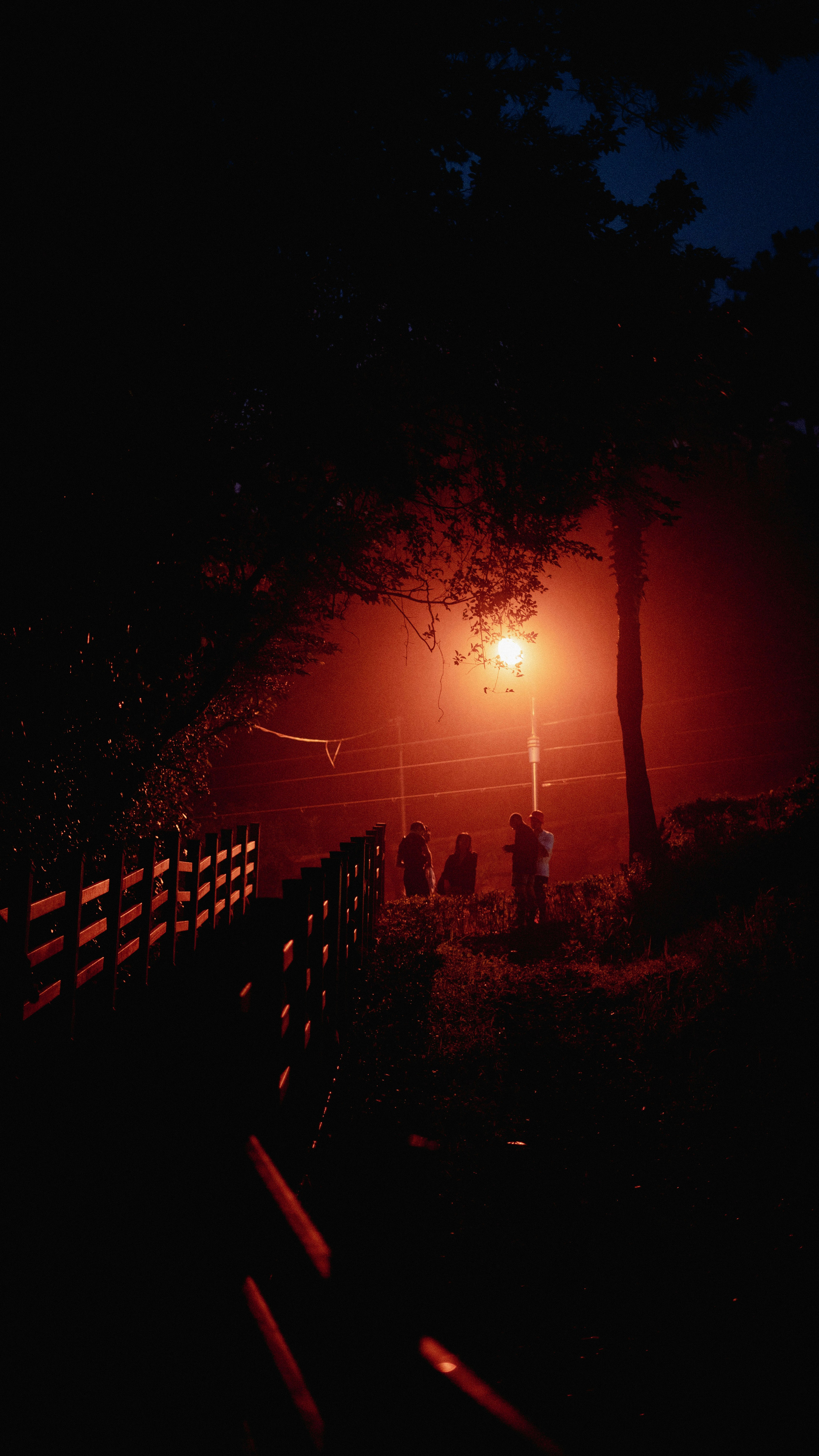 a group of people sitting on a bench under a street light