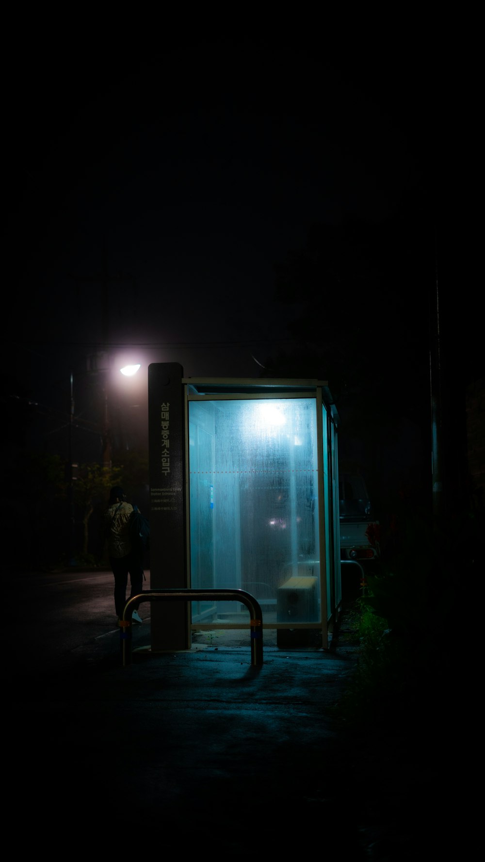 a bus stop at night with a person standing in front of it