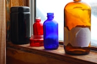 Colorful glass bottles with intricate designs catching the light on a windowsill.