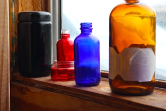 Colorful glass bottles with intricate designs catching the light on a windowsill.