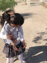A playful scene of siblings wearing coordinated festive outfits in a sunlit Parisian courtyard.
