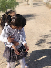 Volunteers warmly embracing children during a community outreach event on a sunny day.
