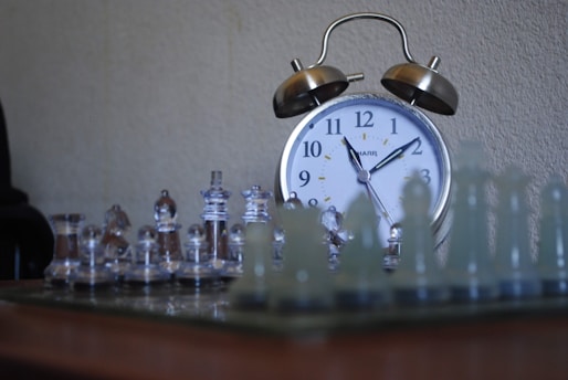 a clock sitting on top of a table next to chess pieces
