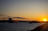 A large cargo ship sailing on the ocean during sunset.