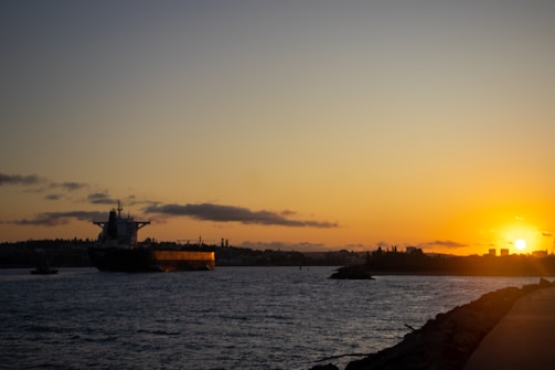 A large cargo ship sailing on the ocean during sunset.