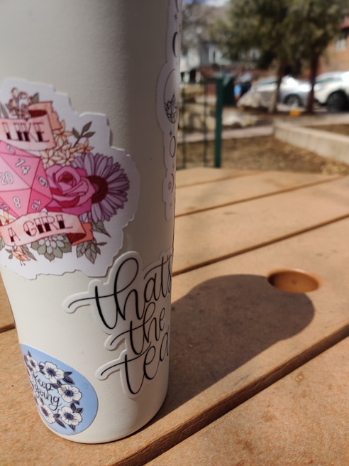 A stainless steel Yeti tumbler sitting on a picnic table with morning sunlight