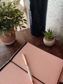 A calm corner with plants and a small wooden table holding a notebook and pen.