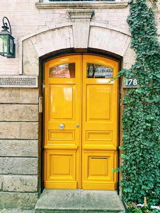 A freshly painted residential door in soft ivory with rose gold hardware gleaming in natural light.