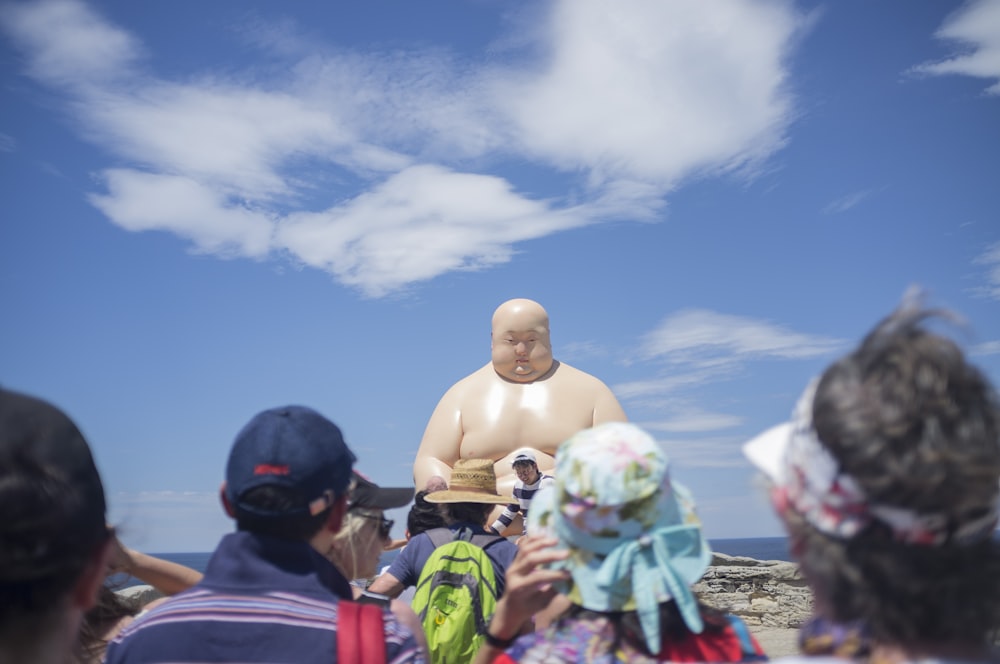 a group of people standing around a statue of a man