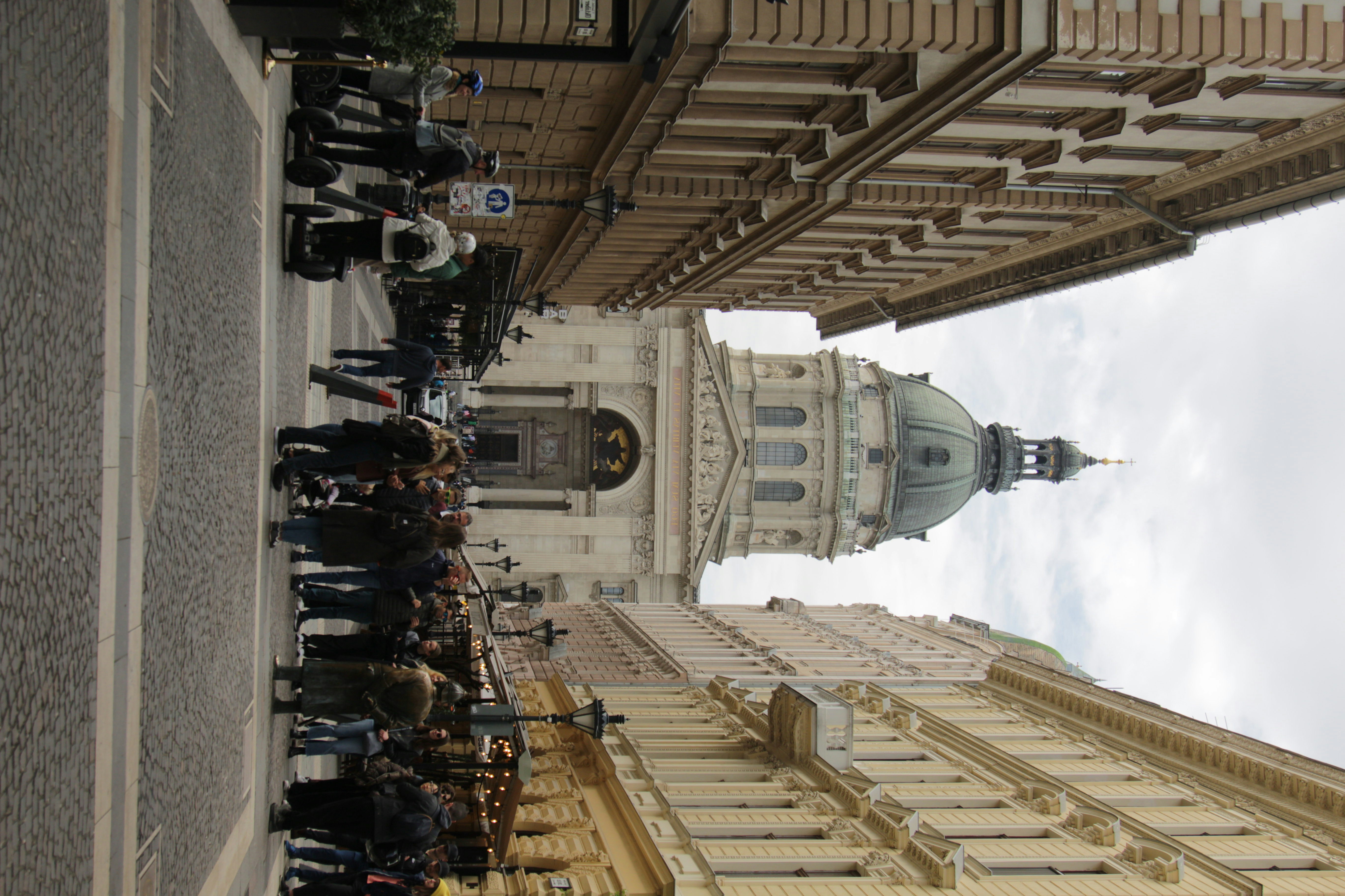 a group of people walking down a street next to tall buildings