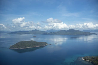 A serene sunrise view over the crystal-clear waters surrounding Pulau Peling, with lush green islands in the distance.