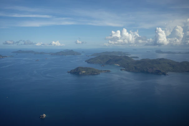 A panoramic shot of lush green islands scattered across the calm sea under a bright blue sky.