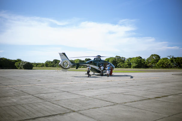 Team members discussing maintenance schedules next to a helicopter on the tarmac.