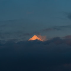 A radiant sunrise breaking through clouds over a sacred mountain.