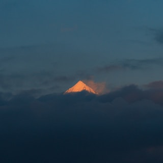 An inspirational photo showing a mountain peak piercing through low clouds.