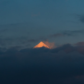 A radiant sunrise breaking through clouds over a sacred mountain.