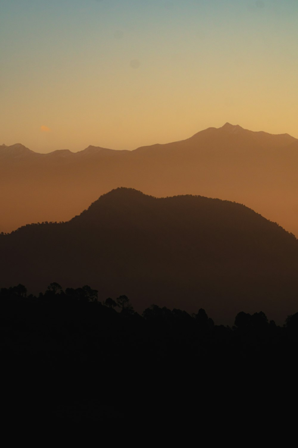 the sun is setting over a mountain range