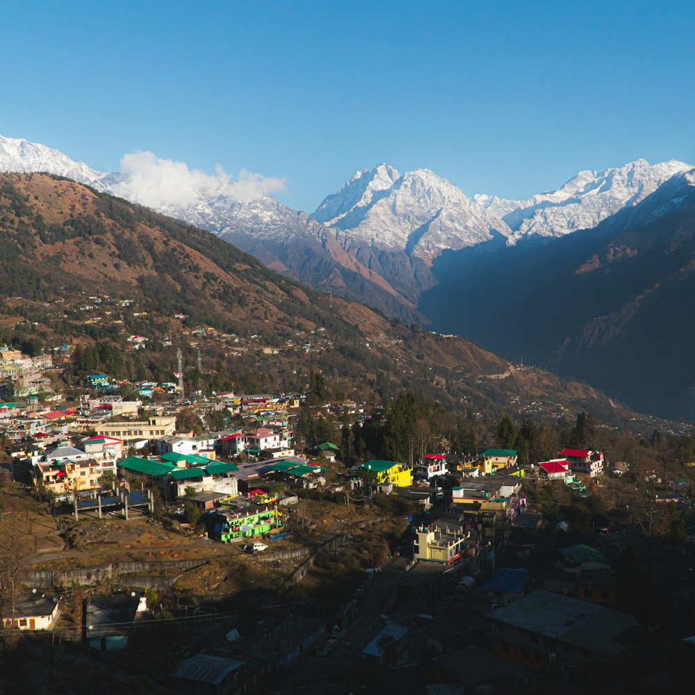 a small village in the mountains with snow capped mountains in the background