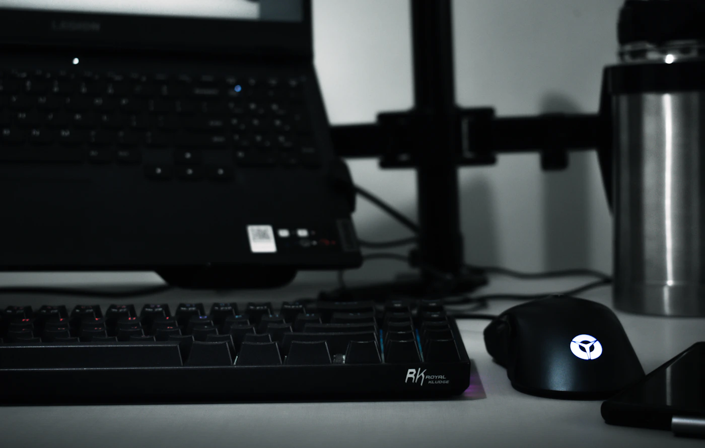 Laptop, keyboard, and mouse arranged on a modern workspace desk