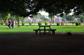 a picnic table in a park with people walking around