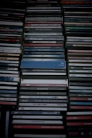 A collection of stacked CD cases, neatly organized in rows with visible labels and album information. The cases exhibit a range of colors and some wear, suggesting a diverse music collection.