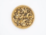 A wooden plate filled with sliced, dried herbal roots displaying various shades of brown and beige, arranged neatly against a plain white background.