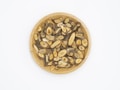 A wooden plate filled with sliced, dried herbal roots displaying various shades of brown and beige, arranged neatly against a plain white background.