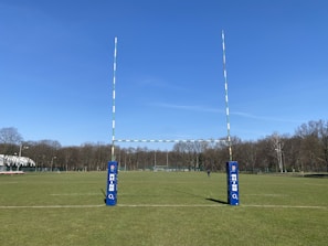 A rugby kit showcased on a field with goal posts in the distance.