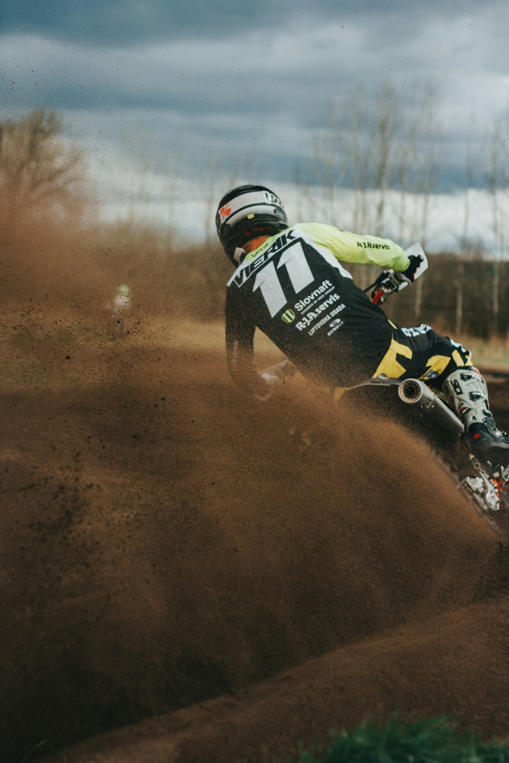 Un hombre montando una moto de cross encima de un campo de tierra