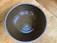 Close-up of a hand holding a rustic, handmade ceramic bowl with subtle earth tones.